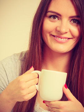Smiling young woman holding cup of tea