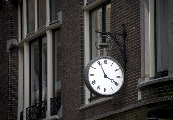 Fototapeta na wymiar street clock hanging from the wall