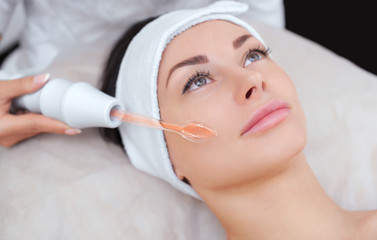 Obraz na płótnie Canvas The cosmetologist makes the procedure Microcurrent therapy of the facial skin of a beautiful, young woman in a beauty salon.Cosmetology and professional skin care.