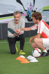 young male footballer in discussion with coach during training