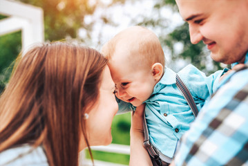 Happy young parents with little son playing outdoor in the park