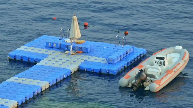 Floating jetty dock over coral reef at the tropical sea resort. Powerboat is moored up to the jetty. Floating jetty docks are used to save the coral reefs and keep it safe.