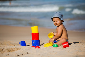 Kid plays with toys at the seashore in summertime
