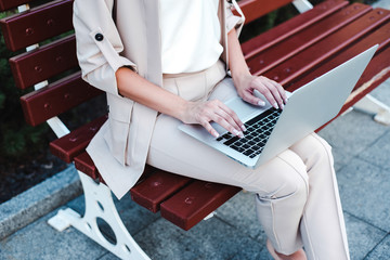 Working hard. Top view part of businesswoman using her laptop while sitting on the bench