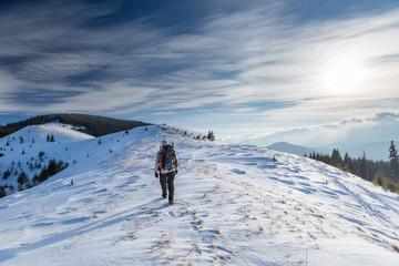 Fototapeta na wymiar Man is backpacking in winter mountains