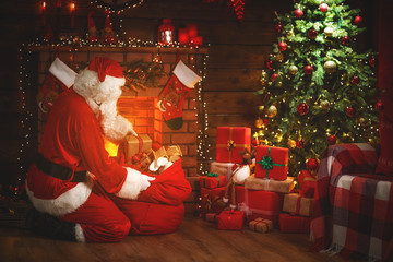 Obraz na płótnie Canvas Merry Christmas! santa claus near the fireplace and tree with gifts