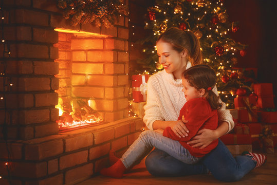 family mother and child  daughter watching   fireplace at Christmas