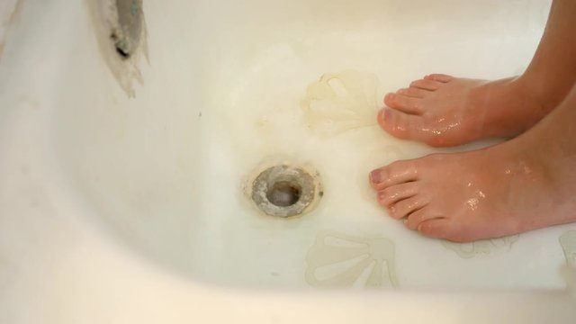Water flows down old ugly shower drain while woman washes up