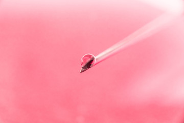 on the tip of a needle from a syringe drop of liquid