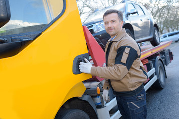 portrait of a tow truck woker with a towed car