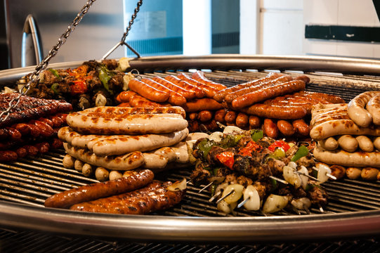 Assortment of grilled sausages and kebabs on big hanging grill at Christmas market in Paris (France).