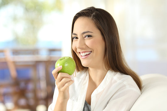 Happy woman holding a healthy apple at home