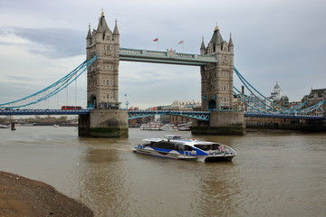 Widok z brzegu Tamizy na rzekę i most Tower Bridge, mała łódź pasażerska  na rzece - obrazy, fototapety, plakaty