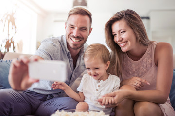 Happy family on their sofa at home take selfie.