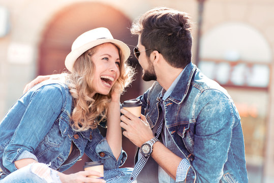 Beautiful young couple enjoying the sun with coffee to go.