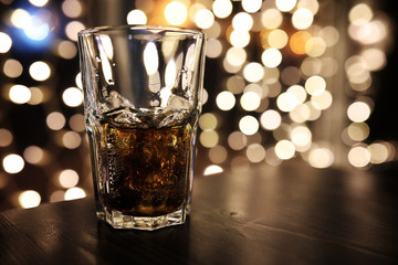 glass of alcohol with ice on blured background with circle bokeh