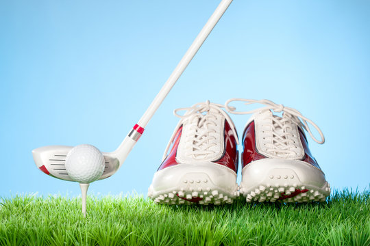 Series of golfing equipment concept pictures..Shot in studio on grass with blue background: Gold Shoes, Ball on Tee and Club