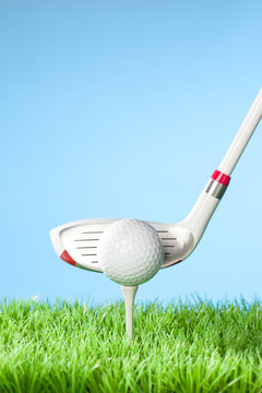 Hybrid driver about to Hit the Ball, Series of golfing equipment concept pictures..Shot in studio on grass with blue background