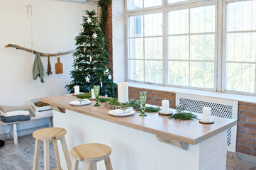 New Year and Christmas 2018. Festive kitchen in Christmas decorations. Candles, spruce branches, wooden stands, table laying.