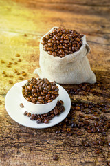 Coffee. A coffee cup with grains and a coffee bag on a wooden table.