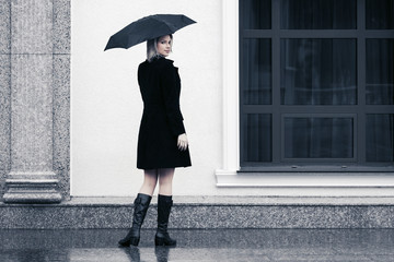 Happy young fashion woman with umbrella walking in city street