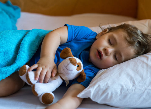 Little baby sleeping with toy in bed at home.