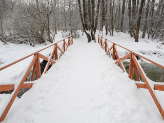 Winter landscape with a bridge across a small river in the park