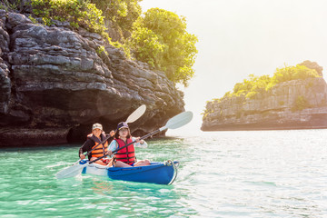Obraz premium Two women are mother and daughter. Travel by boat with a kayak on the sea under sunlight at summer around Ko Phi, view beautiful nature of the sea, Mu Ko Ang Thong National Park, Surat Thani, Thailand