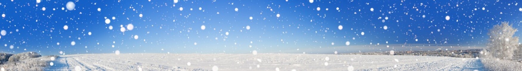rural winter landscape panorama with a field, snow, forest, city and blue sky