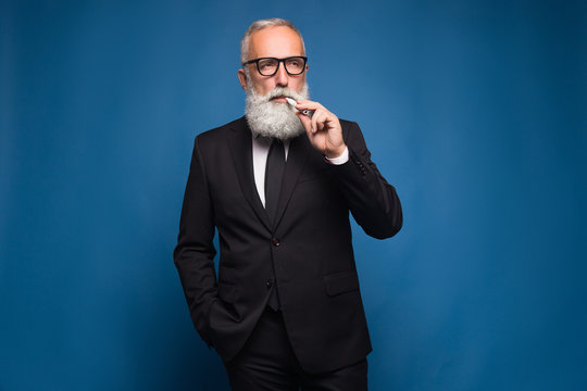 Bearded business man smoking electronic cigarette in the suit. New technology of healthy smoking of electronic vaping cigarette.