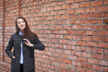 Fototapeta na wymiar Young beautiful girl near red brick wall posing