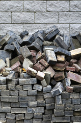 A large pile of disassembled paving tiles against the wall of light bricks