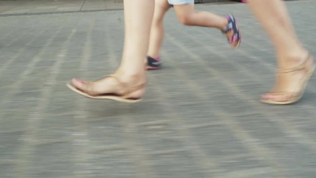 Mother with her little daughter running on the street, feet in movement