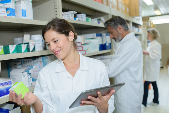 attractive young female pharmacist checking medication