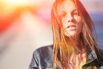 Portrait of stressed sad young woman with disheveled hair in the wind sun on a blurred background, closeup.