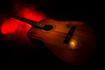 Music concept. Acoustic guitar isolated on a dark background under beam of light with smoke with copy space. Guitar Strings, close up. Selective focus. Fire effects.