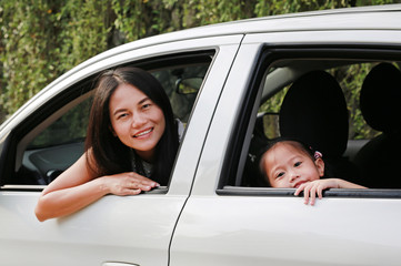 Young woman and her little child girl sitting on a backseat. Family travel concept.