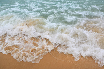 Ocean wave on sandy beach.