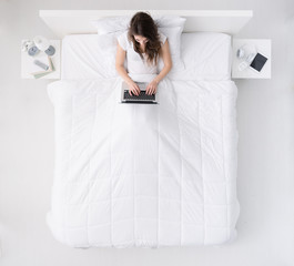 Woman using a laptop on her bed