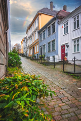 Fototapeta na wymiar Narrow cobble stoned streets between traditional colorful houses in the old part of Bergen