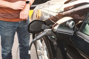 man use smart watch and changing electric car . the modern transportation  technology life.