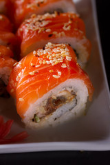 Japanese sushi rolls dish in white plate close up on darkbackground