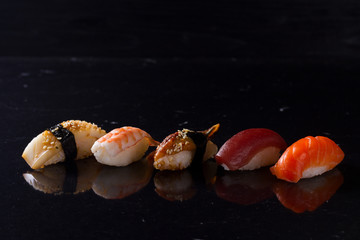 Row of Japanese sushi pieces on black background with copy space