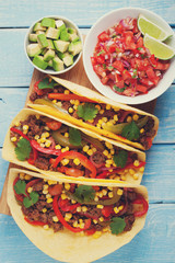 Mexican tacos with minced beef, vegetables and salsa. Tacos al pastor on wooden blue rustic background. Top view