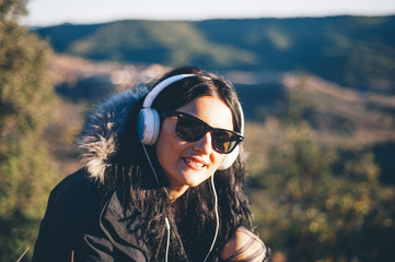 pretty and attractive girl with sunglasses and headphones on the mountain