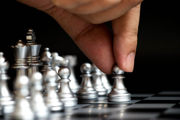 Business man hold pawn to first move in chess game (Concept for company strategy, vision or decision)