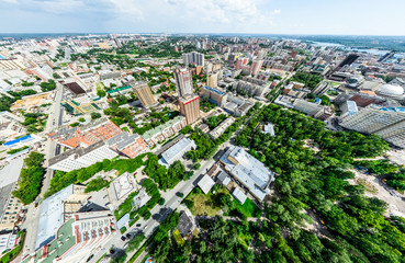 Aerial city view with crossroads and roads, houses, buildings, parks and parking lots, bridges. Helicopter drone shot. Wide Panoramic image.
