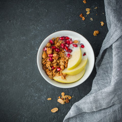 Healthy breakfast. Granola with with pomegranate, green apple and yoghurt in glasses on concrete background. Fresh berries, fresh fruits, homemade granola. Country style. Rustic style. Place for text