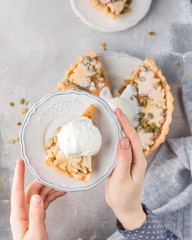 American pumpkin pie, stitched with seeds, powdered sugar and ice cream on a gray light concrete background. Copy Space. View blank space for text. Place for text. photo with hands. Flat lay, top view