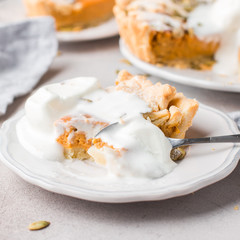 American pumpkin pie, stitched with seeds, powdered sugar and ice cream on a gray light concrete background. Copy Space. View blank space for text. Place for text. photo with hands. Flat lay, top view
